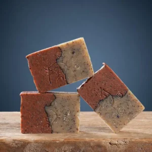 Trois pains de savon exfoliant myrtilles artisanal de la Savonnerie des Monédières en équilibre, marbrage bicolore brun-beige avec pépins visibles