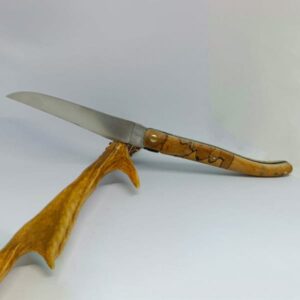 Couteau Laguiole 'Élérable' ouvert, avec un manche en bois d'érable présentant des motifs uniques et une lame en acier 12C27 mate avec guillochage délicat. Le couteau repose sur un support en bois naturel, ce qui met en valeur la finesse de la lame et le dessin particulier du manche. L'assemblage soigné du bois et de l'acier illustre le savoir-faire artisanal de Laguiole Laffont.