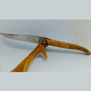 Couteau Laguiole 'Élérable' ouvert, montrant la lame en acier 12C27 ornée de gravures délicates et le manche en bois d'érable aux motifs complexes et naturels. L'angle de la photo révèle les détails guillochés du ressort en inox et la finition méticuleuse de l'assemblage. Le fond neutre met en valeur l'artisanat précis et la beauté des matières utilisées par Laguiole Laffont.