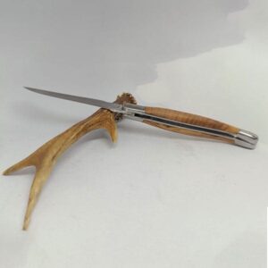 "Couteau Laguiole Château Virant de 12 cm avec manche en bois d'olivier, présenté ouvert. Le manche présente des veines naturelles et une teinte chaleureuse caractéristique du bois d'olivier. La lame en acier inoxydable poli brille à côté de la platine simple et des mitres en inox. Un ressort guilloché avec une abeille forgée ajoute un détail emblématique au design élégant. L'arrière-plan est neutre, mettant en valeur le couteau artisanal.