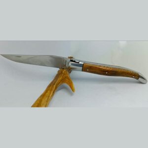 Couteau Laguiole 'L'Outil' de 12 cm fabriqué par Laguiole Laffont, présenté ouvert. Il arbore une lame lisse en acier inoxydable satiné et un manche en bois de châtaignier aux veines prononcées. Les mitres en inox satiné ajoutent une touche de sophistication au design épuré du couteau, reflétant la qualité artisanale de Laguiole Laffont. Le couteau est photographié sur un fond clair qui accentue ses détails fins et l'éclat métallique.