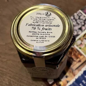 Vue du dessus d'un pot de confiture artisanale myrtilles cannelle de 200g. L'étiquette mentionne "Fabrication artisanale 70 % fruits" et précise les informations nutritionnelles pour 100g : 155 kcal, 0 g de graisses, 37 g de glucides dont 34 g de sucres, 0,5 g de protéines. Les ingrédients incluent des myrtilles, de la cannelle, du sucre et de la pectine de pomme.