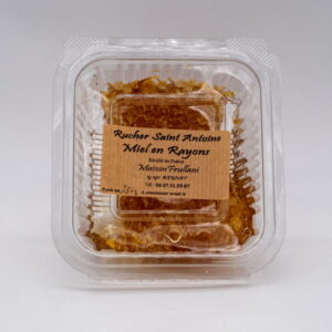 Miel en Rayon du Rucher Saint-Antoine présenté dans une boîte transparente, avec une étiquette artisanale. Miel brut encapsulé dans de la cire naturelle, récolté en Corrèze.