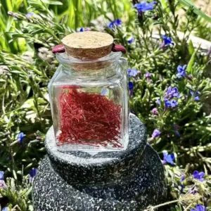 Pot en verre de pur safran bio en stigmates 1 g cultivé en Corrèze, épice artisanale française, flacon scellé avec bouchon en liège, posé sur mortier en pierre.