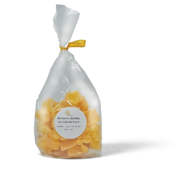 Sachet transparent noué d'un ruban doré contenant des bonbons au miel de thym couleur jaune ambrée, fabriqués par Au Jardin de Magali à la miellerie artisanale de Jassans-Riottier dans l'Ain